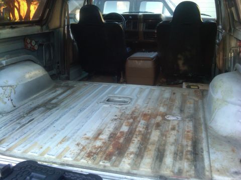 1986 Ford Bronco - The cargo area of a 1986 Ford Bronco, worn metal flooring and the rear seats visible.