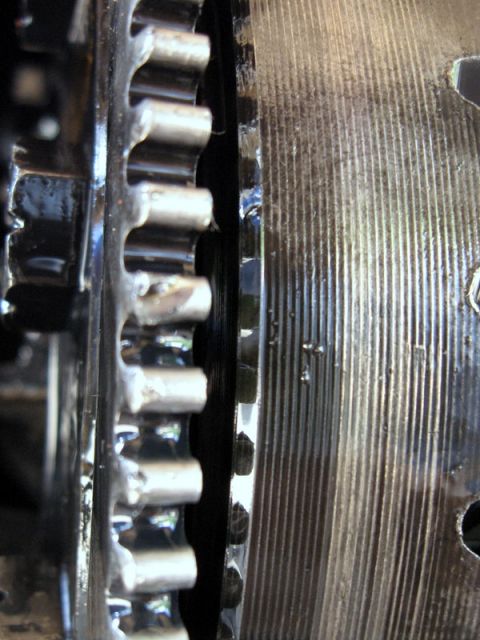 1995 Ford F-150 - Extreme close-up of a flywheel's ring gear teeth beside the freshly machined clutch friction surface, the resurfaced steel face showing fin…