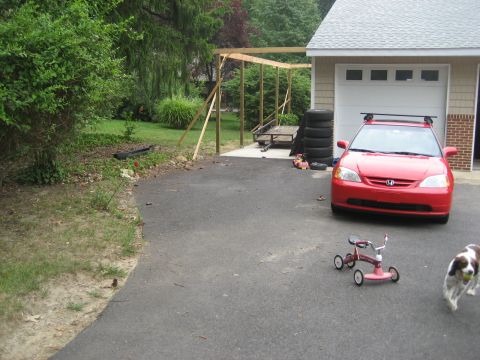 1996 Ford Bronco - A red sedan is parked on a driveway next to a garage, with a dog and a tricycle nearby.