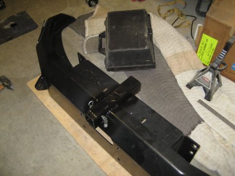 1996 Ford Bronco - A black metal bumper assembly and a black electrical box are laid out on a blanket, with tools and jack stands nearby.