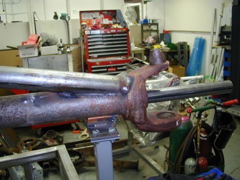 1979 Ford Bronco - A close-up view of a rusty metal axle component, likely part of a vehicle's suspension or drivetrain, resting on a stand in a workshop envi…