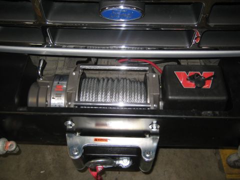 1996 Ford Bronco - A winch is mounted to the front bumper of a vehicle, with a red Warn Industries logo visible.
