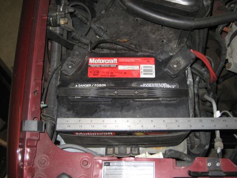 1996 Ford Bronco - Close-up of a car battery in an engine bay, with a ruler for scale.