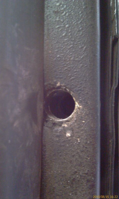 1994 Ford Bronco - A close-up view of a metal component, possibly from a vehicle's interior structure, showing a drilled hole.