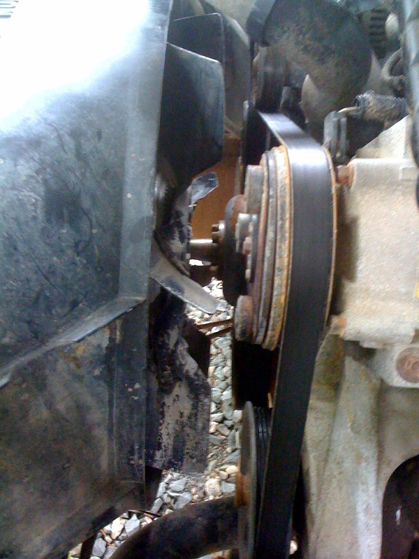 Engine belt and pulley system with a fan blade visible on the left