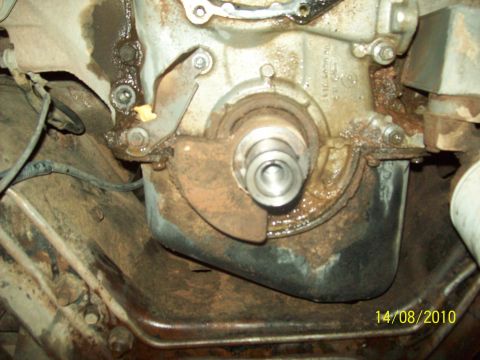 1985 Ford Bronco - A close-up view of a vehicle's engine crankshaft seal area, showing signs of wear and grease.