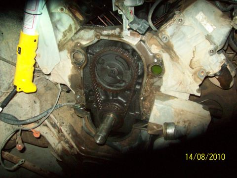1985 Ford Bronco - Close-up of an engine with the timing chain cover removed, revealing internal components.