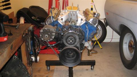 1968 Ford Ranchero - Engine assembly for a 1968 Ford Ranchero, displayed on a stand beside the vehicle's fender.