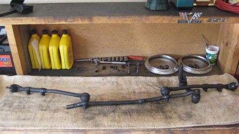 1968 Ford Ranchero - Various steering linkage components are displayed on a workbench alongside tools and yellow oil bottles.