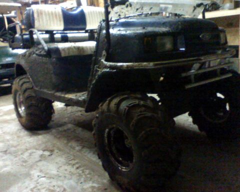 1978 Ford F-150 - A heavily modified golf cart, covered in mud, sits in a workshop.