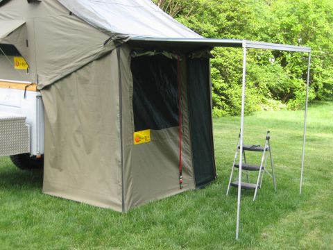1996 Ford Bronco - A camper trailer's awning is deployed, with a portable ladder positioned on the grass next to it.