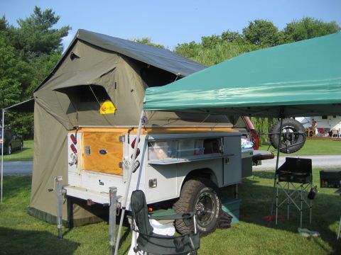 1996 Ford Bronco - A campsite scene a trailer equipped with a rooftop tent and an outdoor kitchen setup.