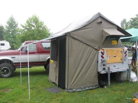 1996 Ford Bronco - A 1996 Ford Bronco is parked next to a pop-up camper trailer set up on a grassy area.
