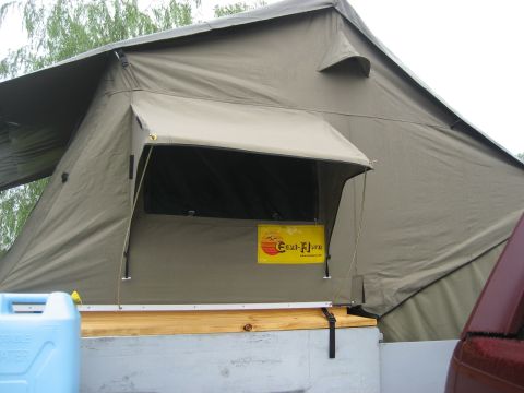 1996 Ford Bronco - A pop-up camper tent is attached to a trailer, with a blue water jug visible on the left.