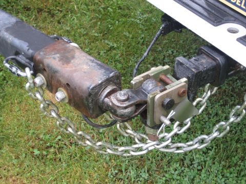 1996 Ford Bronco - Close-up view of a trailer hitch and safety chains connected to a vehicle's receiver, with grass in the background.
