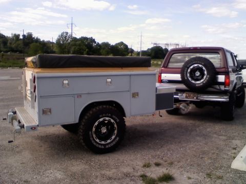 1996 Ford Bronco - A maroon Ford Bronco is parked behind a custom utility trailer with a roll-up cover.
