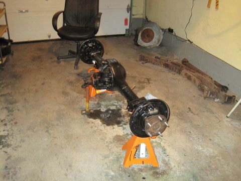1979 Ford Bronco - A disassembled rear axle assembly is shown on jack stands in a garage setting.