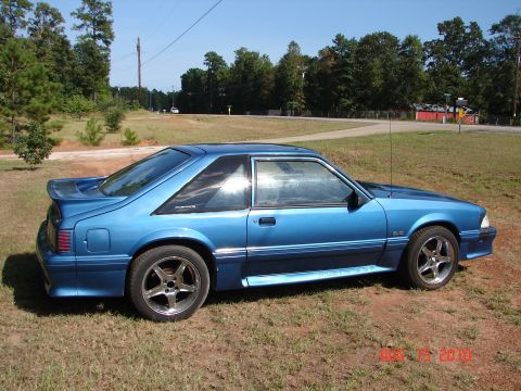 1987 Ford Bronco - Blue 1987 Ford Mustang hatchback with a spoiler and 5-spoke wheels parked outdoors.