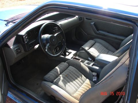 1987 Ford Bronco - The interior of a blue car is shown, plaid fabric seats and a dark dashboard.