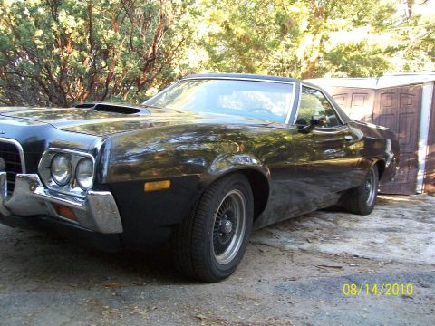 1972 Ford Ranchero - Black 1972 Ford Ranchero with a hood scoop is parked in front of a shed.