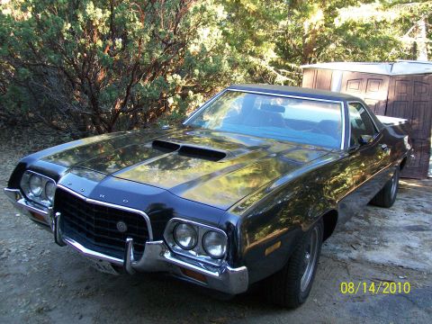 1972 Ford Ranchero - A 1972 Ford Ranchero is parked outside next to a wooden shed and some trees.