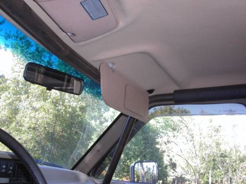 1990 Ford Bronco II - The interior of the vehicle shows a sun visor, rearview mirror, and a portion of the steering wheel.