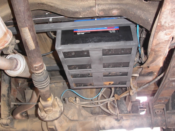 Battery carrier seen from underneath.

With the large hole cut in the floorboard, I ran a brace underneath the floor to restore the floor's rigidity (it's the one visible above the driveshaft having the nut on it).