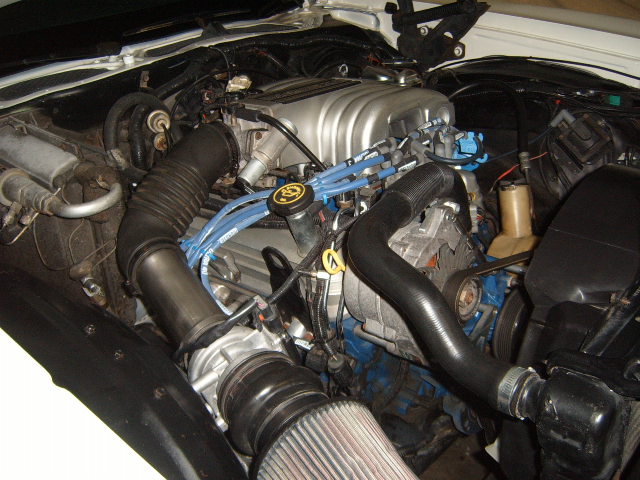 Engine bay showing V8 engine, air intake, and hoses