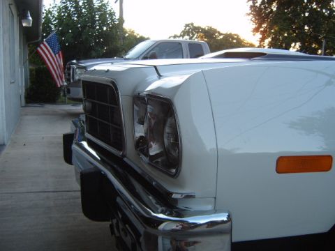 1973 Ford Ranchero - The front quarter of a white 1973 Ford Ranchero is shown, a prominent hood scoop and chrome bumper.