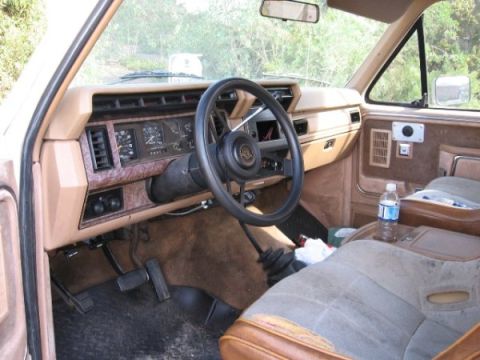 1986 Ford Bronco - Interior of an early 1980s Ford Bronco, a tan dashboard and cloth seats.