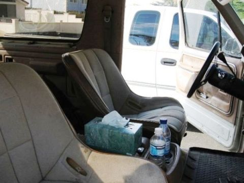 1986 Ford Bronco - Interior view of a vehicle with bucket seats and a tissue box, next to a white truck.