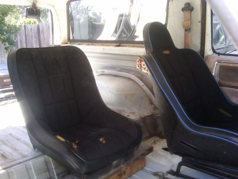1986 Ford Bronco - The interior of a vehicle features two worn bucket seats, with the rear cargo area visible.