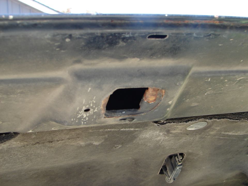 Underside of a car hood showing rust around a mounting hole. Supermotors.net logo visible
