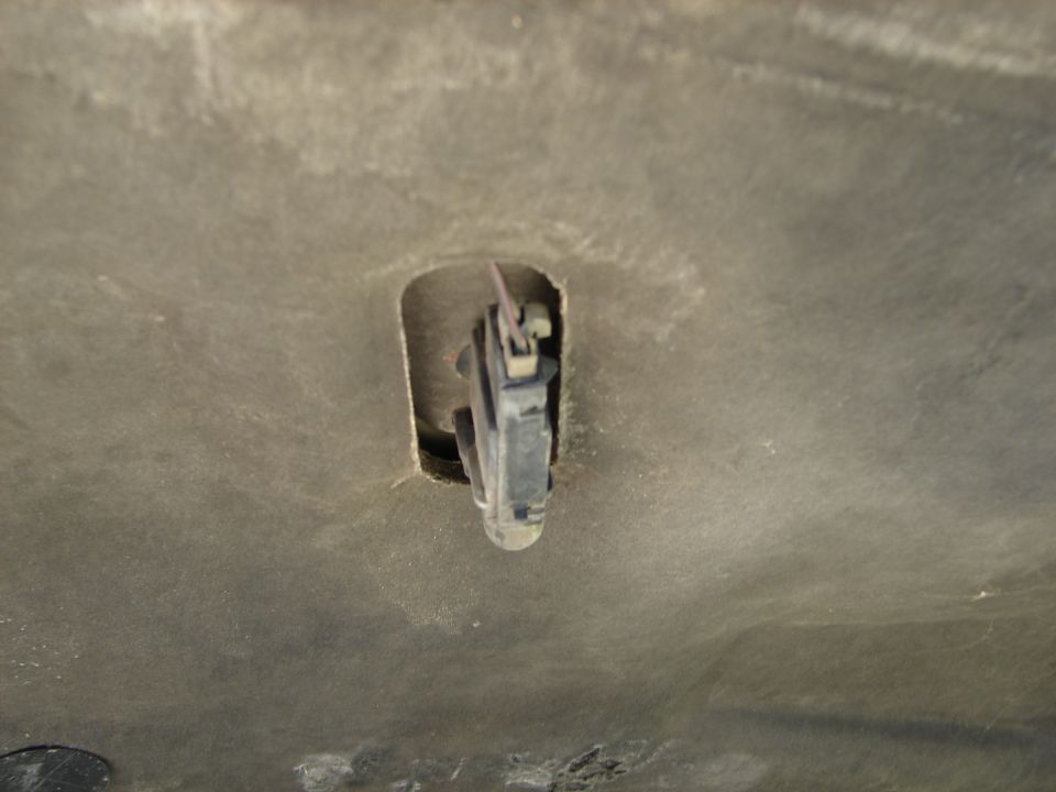 Underneath a 1992 Ford Taurus hood, a hood latch mechanism is visible in a cutout