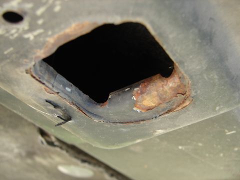 1992 Ford Taurus - Close-up of rust and a hole in a vehicle's metal panel.
