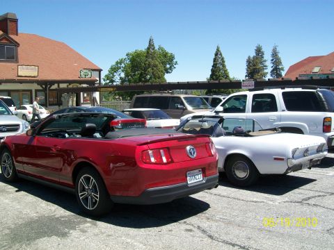 1968 Ford Mustang - Two Mustangs, one modern and one classic, are parked side-by-side in a lot.