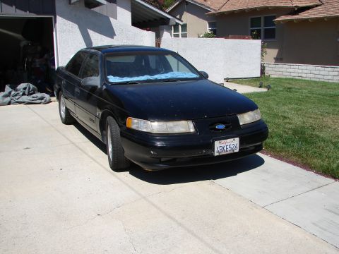 1992 Ford Taurus - This black 1992 Ford Taurus is parked in a driveway, showing its front 3/4 view. The California license plate is visible.