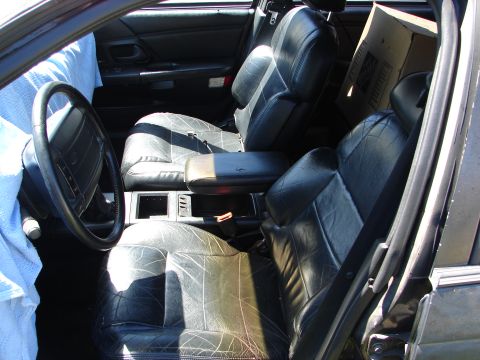 1992 Ford Taurus - The interior of a car shows worn leather seats and a steering wheel, with a cardboard box placed in the rear.