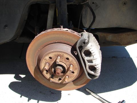 1992 Ford Taurus - A close-up view of a car's brake system, showing a rusty rotor and caliper.