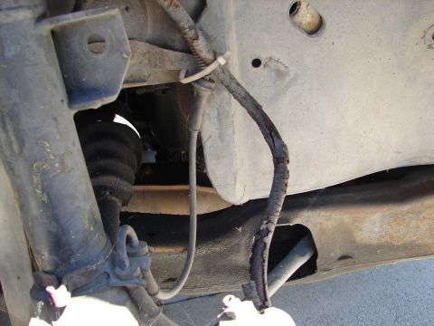 1992 Ford Taurus - Close-up of a vehicle's undercarriage reveals a damaged brake line and suspension parts.