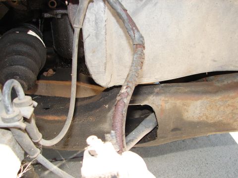 1992 Ford Taurus - Close-up view of corroded wiring and suspension components on the underside of a vehicle.