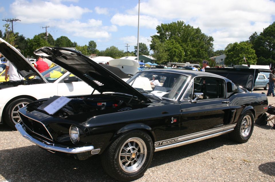 Black 1968 Shelby GT500KR with hood open, parked at an outdoor car show