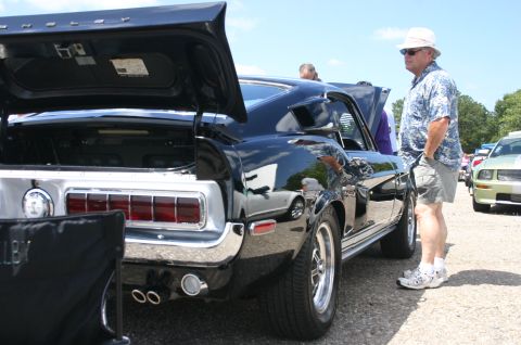 1968 Shelby GT500 - A black 1968 Shelby GT500 is displayed with its trunk open at a car show, with spectators nearby.