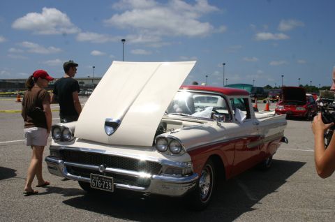 1968 Shelby GT500 - A two-tone red and cream 1957 Ford F-100 pickup truck is displayed with its hood open at a car show.