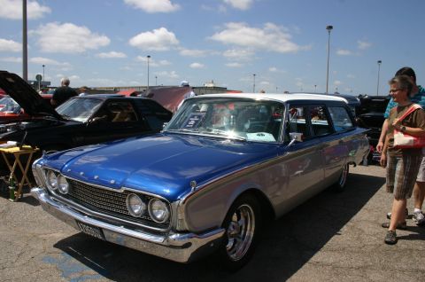 1968 Shelby GT500 - A blue and silver station wagon is parked at a car show, with other vehicles and people in the background.