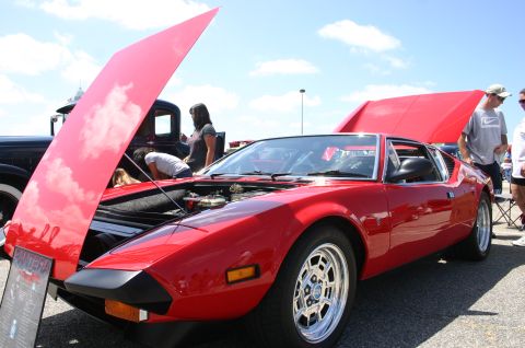 1968 Shelby GT500 - A red de Tomaso Pantera is displayed with both hoods open, revealing the engine and interior at a car show.