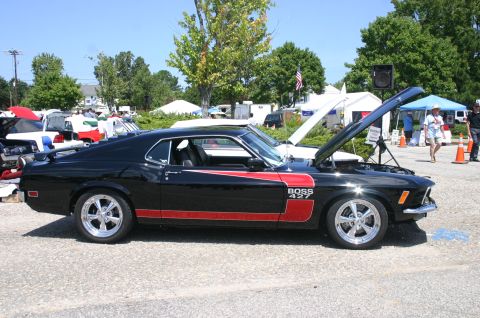 1968 Shelby GT500 - A black 1969 Ford Mustang Boss 427 is displayed with its hood open at a car show, alongside other vehicles and tents.