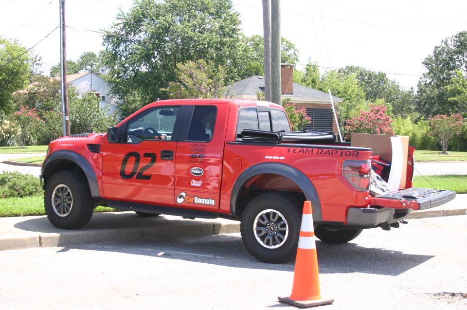 Red Ford F-150 SVT Raptor pickup truck with "02" on the door and "TEAM RAPTOR" on the tailgate