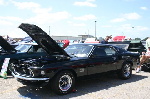 1968 Shelby GT500 - A black 1969 Ford Mustang Boss 429 is displayed with its hood open at a car show, alongside other vehicles.