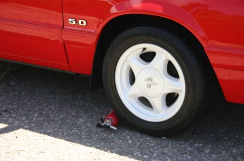 1968 Shelby GT500 - A red Ford Mustang 5.0 is parked on asphalt, with a fire extinguisher near the front wheel.
